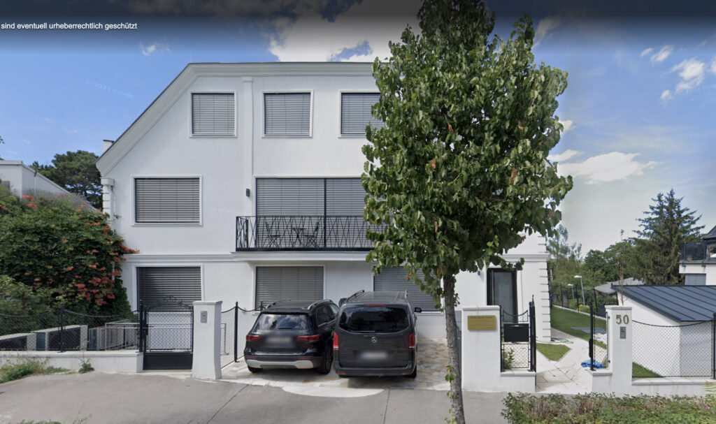 Vorderansicht der Klinik Harik-Chraim, ein weisses Haus mit grauen Rolläden, davor ein grüner Baum und zwei Autos